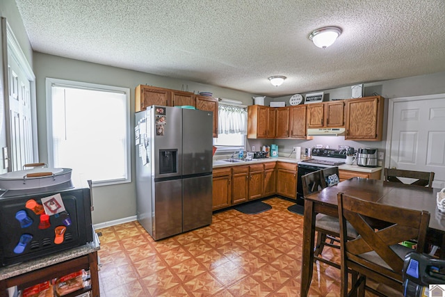 1040 Weda Cir, Mayfield, KY 42066 - kitchen with stainless steel fridge, electric range, under cabinet range hood, light countertops, and brown cabinetry