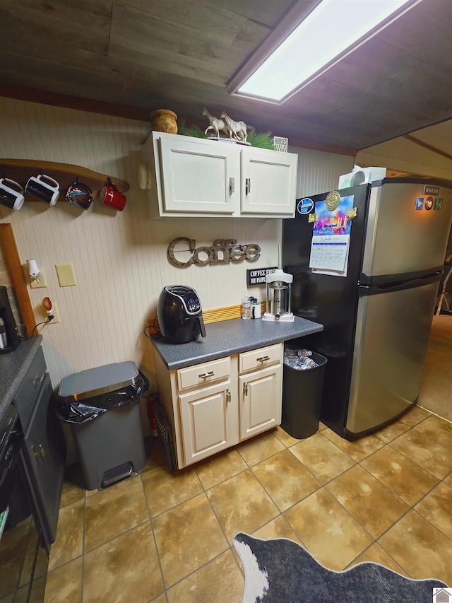 1040 Shine Ln, Cadiz, KY 42211 - kitchen with freestanding refrigerator, light tile patterned floors, dark countertops, white cabinetry, and wooden walls