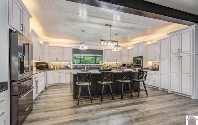 1 Logan Trl, Murray, KY 42071 - kitchen with appliances with stainless steel finishes, light wood finished floors, a breakfast bar, backsplash, and a center island