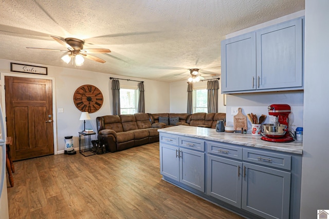 1715 State Route 80 W, Arlington, KY 42021 - kitchen with ceiling fan, a textured ceiling, wood finished floors, a peninsula, and open floor plan