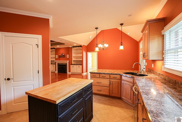 329 Royal Park Dr, Calvert City, KY 42029 - kitchen with wooden counters, a fireplace, decorative light fixtures, light tile patterned floors, and lofted ceiling