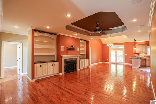 329 Royal Park Dr, Calvert City, KY 42029 - unfurnished living room with ceiling fan, ornamental molding, a tiled fireplace, light wood-style floors, and a tray ceiling