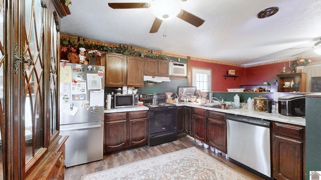 233 Bendefield Ln, Farmington, KY 42040 - kitchen with appliances with stainless steel finishes, a ceiling fan, under cabinet range hood, light countertops, and wood finished floors