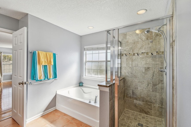 bathroom with shower with separate bathtub, tile patterned flooring, and a textured ceiling