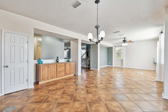 interior space with tile patterned flooring, ceiling fan with notable chandelier, and a textured ceiling