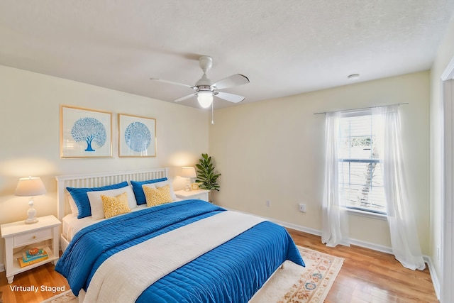 bedroom with ceiling fan, a textured ceiling, and light hardwood / wood-style floors