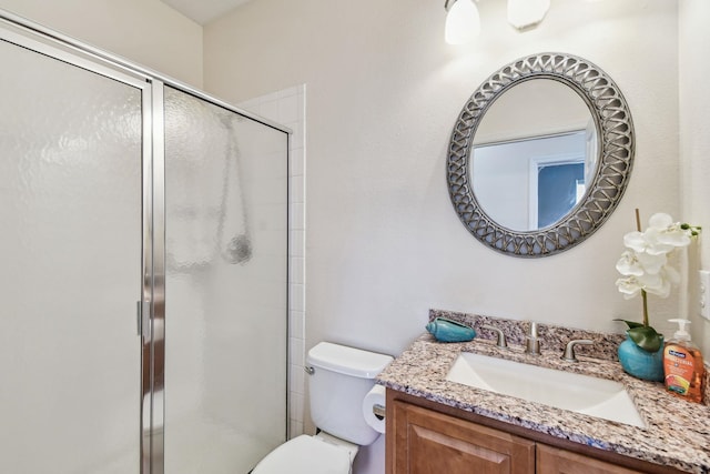 bathroom with a shower with door, vanity, and toilet