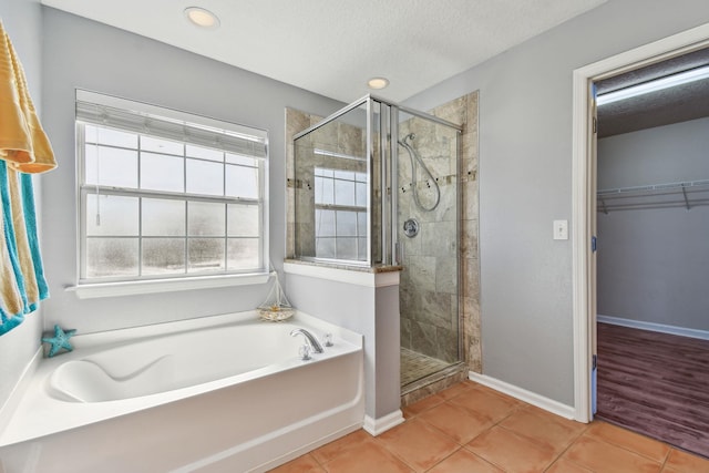 bathroom with a textured ceiling, tile patterned floors, and separate shower and tub