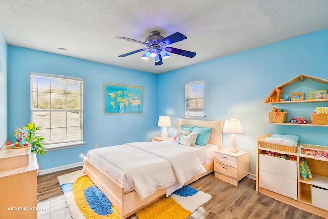 bedroom with ceiling fan, wood-type flooring, and a textured ceiling