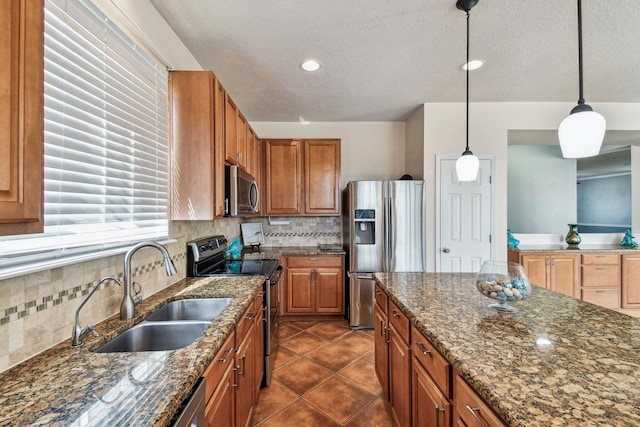 kitchen featuring sink, tasteful backsplash, hanging light fixtures, dark stone counters, and stainless steel appliances