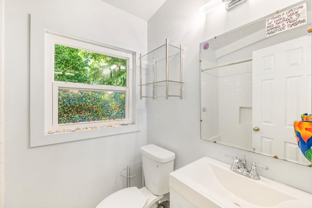 bathroom with toilet, a tile shower, and vanity