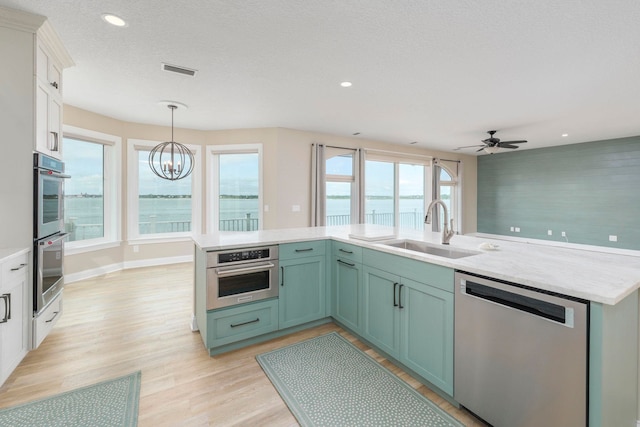 kitchen with pendant lighting, sink, light hardwood / wood-style floors, white cabinetry, and stainless steel appliances