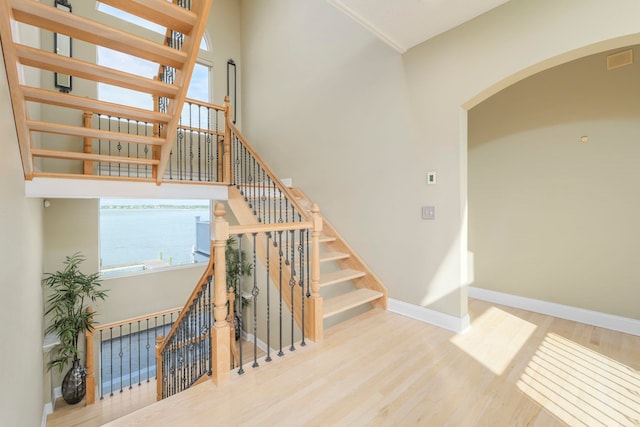 stairs with hardwood / wood-style floors and a water view