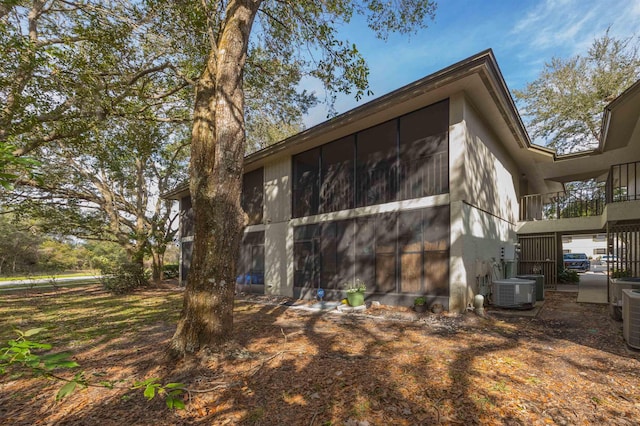 view of side of home featuring cooling unit, a balcony, and a sunroom