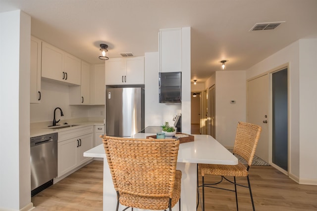 kitchen featuring sink, a breakfast bar, white cabinets, and appliances with stainless steel finishes