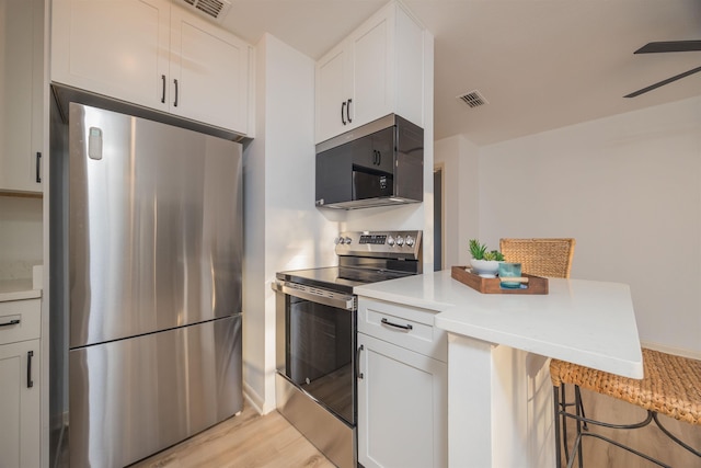 kitchen featuring white cabinetry, appliances with stainless steel finishes, and a kitchen bar