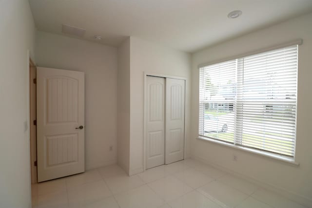 unfurnished bedroom with a closet, light tile patterned floors, and multiple windows