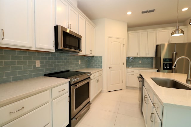 kitchen with white cabinets, appliances with stainless steel finishes, decorative light fixtures, and decorative backsplash