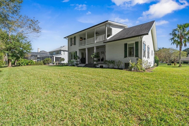 back of property with a lawn, ceiling fan, a balcony, and central AC