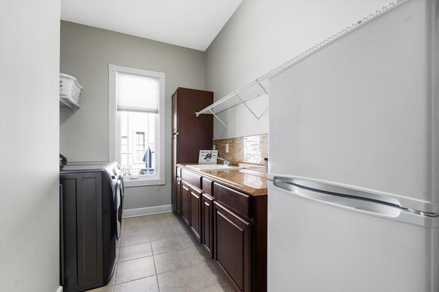 laundry area with washing machine and dryer, sink, and light tile patterned floors