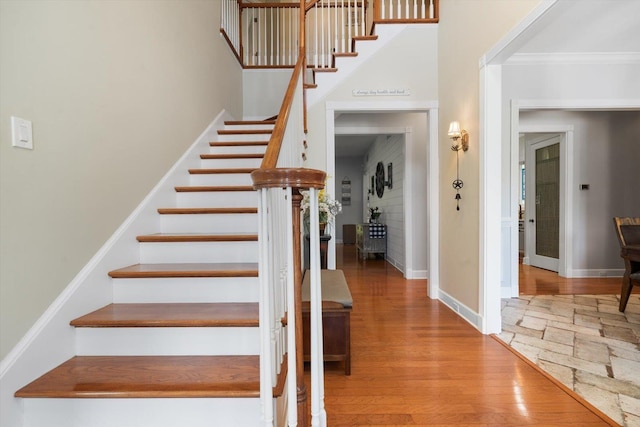 stairway featuring wood-type flooring and ornamental molding