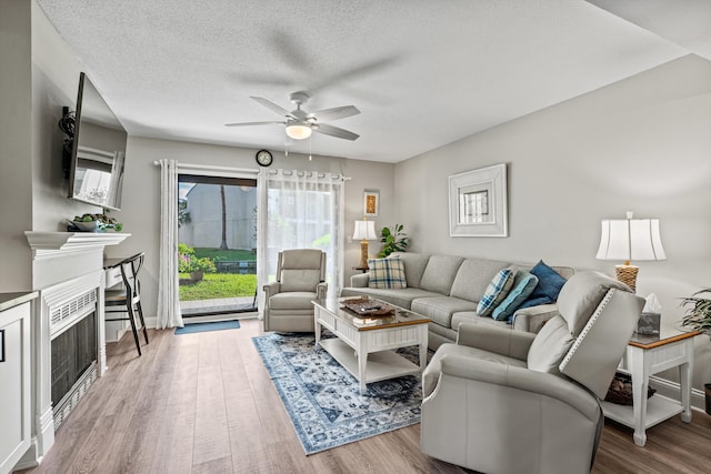 living room with ceiling fan, hardwood / wood-style floors, and a textured ceiling