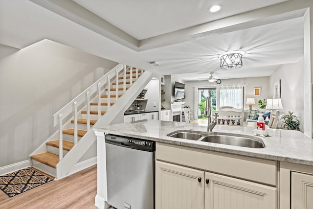 kitchen with sink, light stone counters, dishwasher, light hardwood / wood-style floors, and cream cabinetry