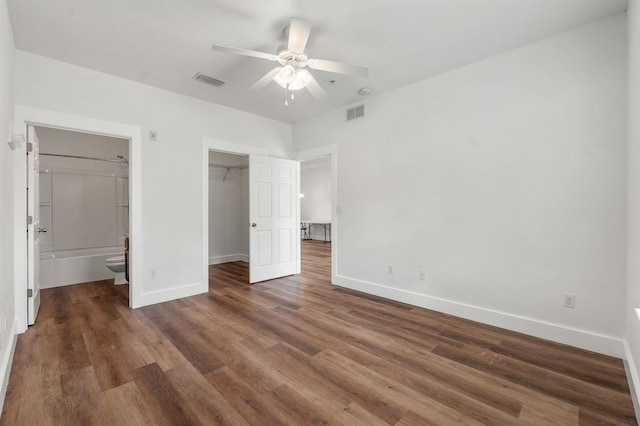 unfurnished bedroom featuring dark wood-type flooring, visible vents, baseboards, a spacious closet, and a closet