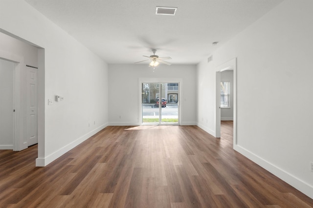 interior space featuring dark wood-style flooring, visible vents, ceiling fan, and baseboards