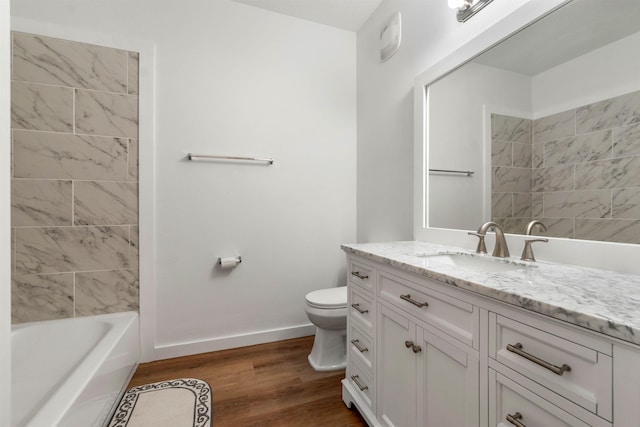 bathroom featuring baseboards, toilet, wood finished floors, vanity, and shower / washtub combination