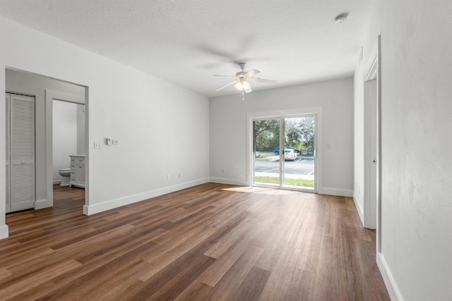 unfurnished bedroom featuring access to exterior, a textured ceiling, baseboards, and dark wood-type flooring