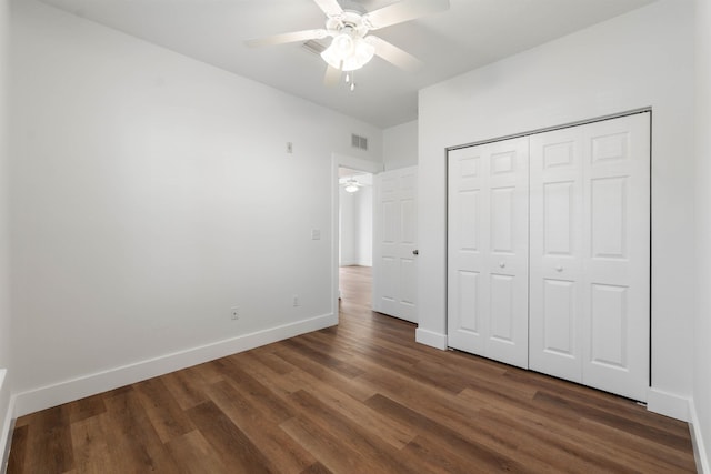 unfurnished bedroom featuring dark wood-style floors, a closet, visible vents, a ceiling fan, and baseboards