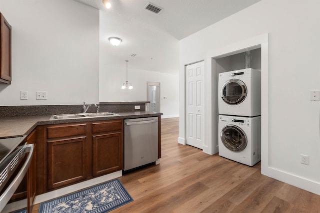 kitchen featuring appliances with stainless steel finishes, stacked washer and dryer, visible vents, and dark countertops