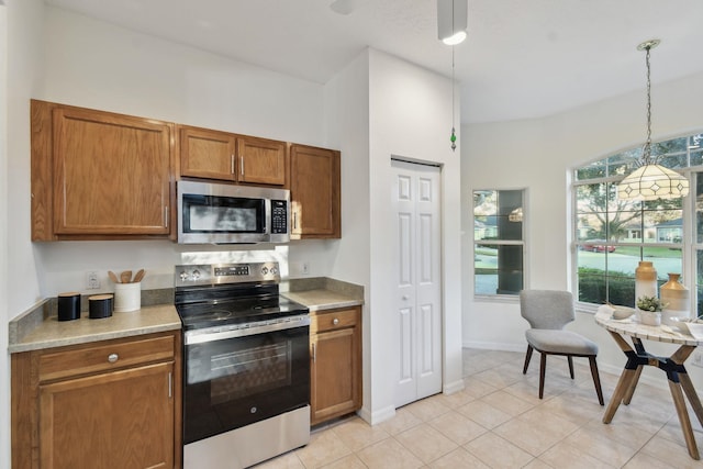 581 Boxwood Pl, Saint Augustine, FL 32086 - kitchen with stainless steel appliances, brown cabinets, light countertops, and hanging light fixtures
