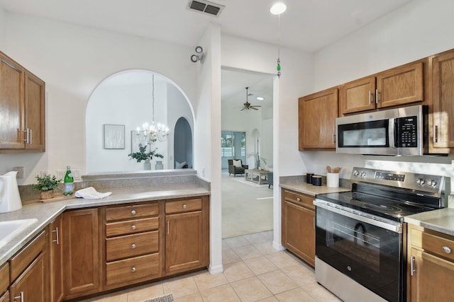 581 Boxwood Pl, Saint Augustine, FL 32086 - kitchen featuring appliances with stainless steel finishes, a ceiling fan, arched walkways, brown cabinets, and light countertops