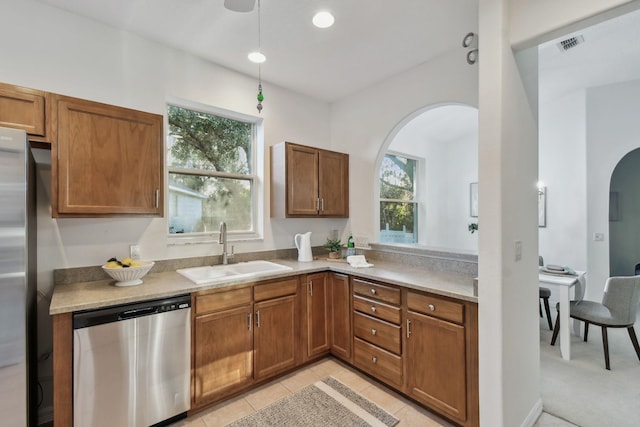 581 Boxwood Pl, Saint Augustine, FL 32086 - kitchen with stainless steel appliances, arched walkways, light countertops, and brown cabinets