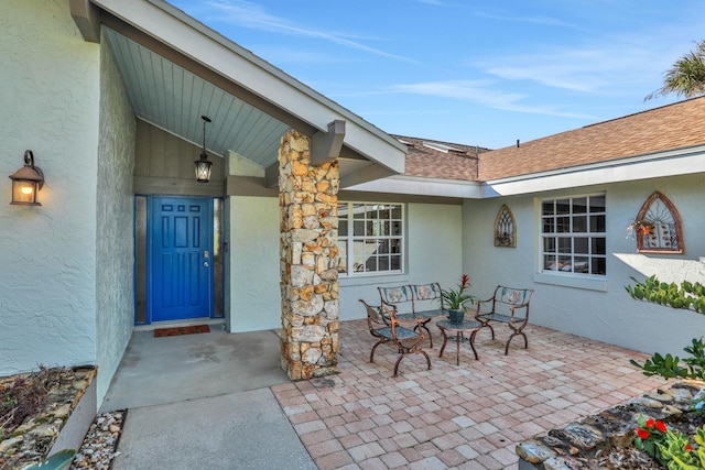 doorway to property with a shingled roof and stucco siding