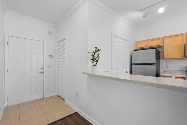 kitchen with light tile patterned floors, crown molding, and stainless steel fridge