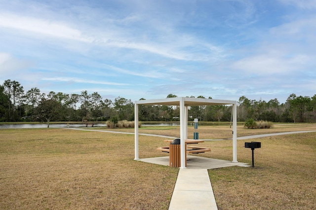 surrounding community with a water view and a lawn