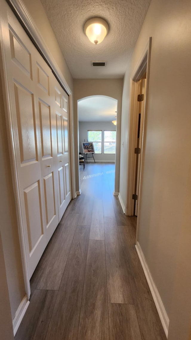 708 Blackmoor Gate Ln, Saint Augustine, FL 32084 - corridor featuring arched walkways, a textured ceiling, dark wood-style flooring, and baseboards