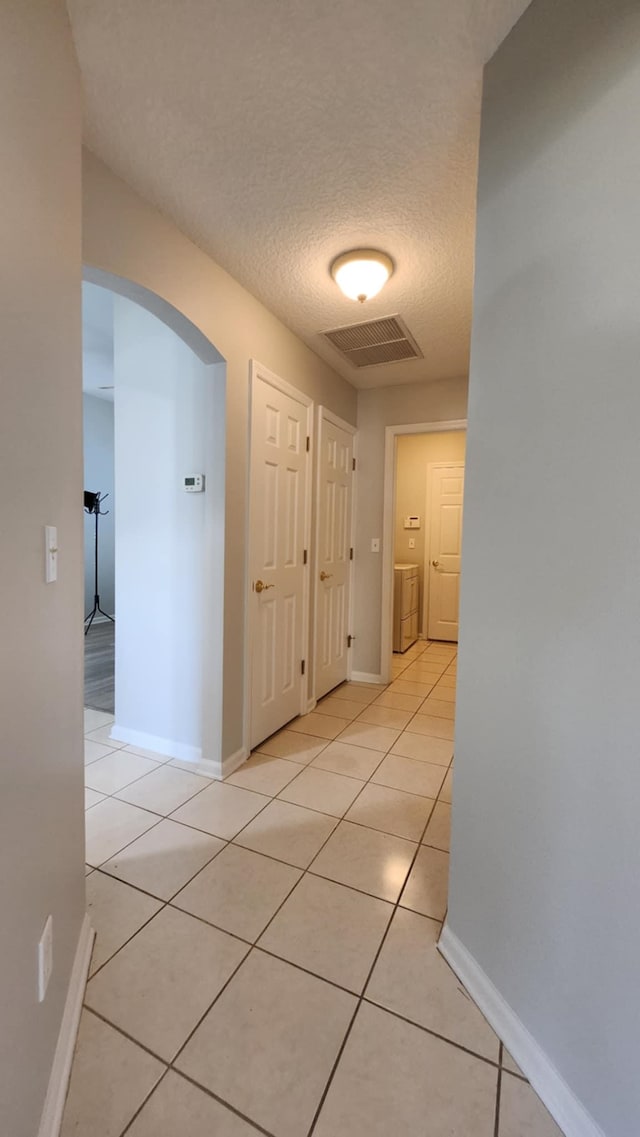 708 Blackmoor Gate Ln, Saint Augustine, FL 32084 - hall featuring arched walkways, a textured ceiling, light tile patterned floors, baseboards, and washer / clothes dryer