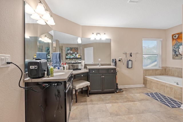 bathroom with vanity, a textured ceiling, and tiled bath