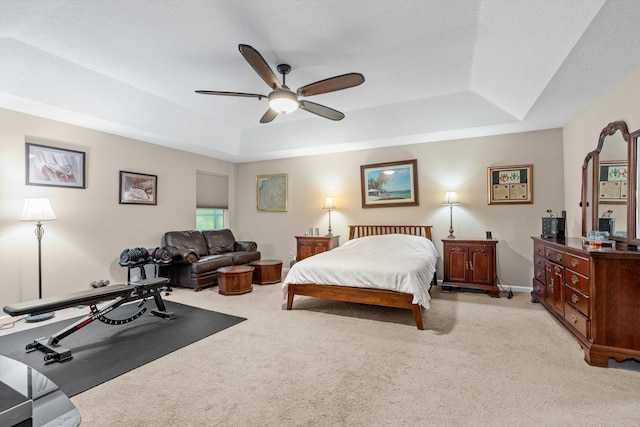 bedroom with a tray ceiling, ceiling fan, and light carpet