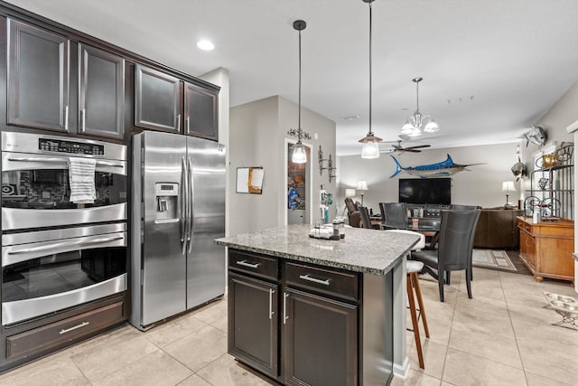 kitchen featuring appliances with stainless steel finishes, dark brown cabinetry, ceiling fan, pendant lighting, and a kitchen island