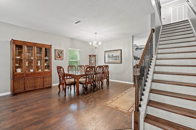 dining area featuring a textured ceiling, ceiling fan with notable chandelier, and dark wood-type flooring