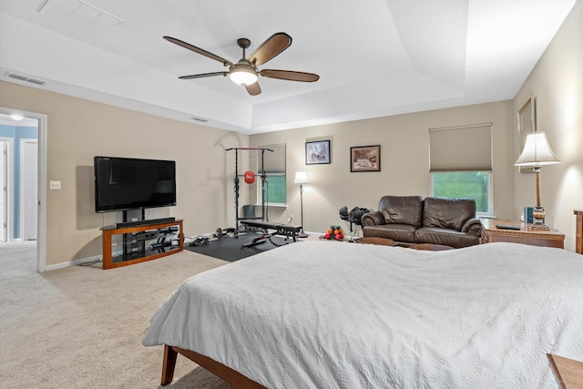 carpeted bedroom featuring a tray ceiling and ceiling fan