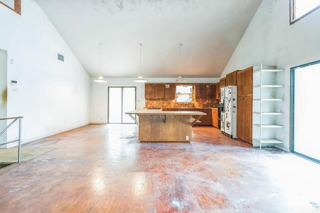 19 Casanova Rd, Saint Augustine, FL 32080 - kitchen with high vaulted ceiling, brown cabinetry, tasteful backsplash, white refrigerator with ice dispenser, and pendant lighting