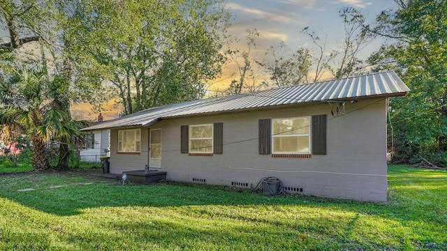 back house at dusk featuring a lawn