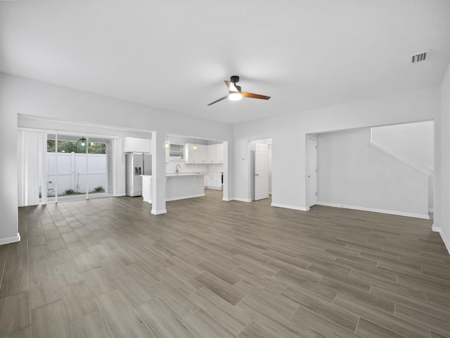 unfurnished living room featuring wood-type flooring and ceiling fan