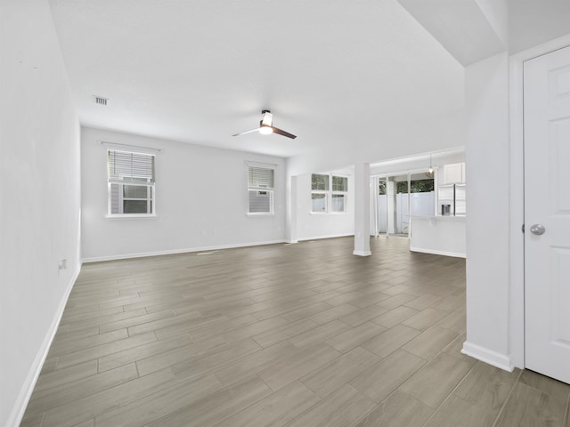 unfurnished living room featuring light wood-type flooring, plenty of natural light, and ceiling fan